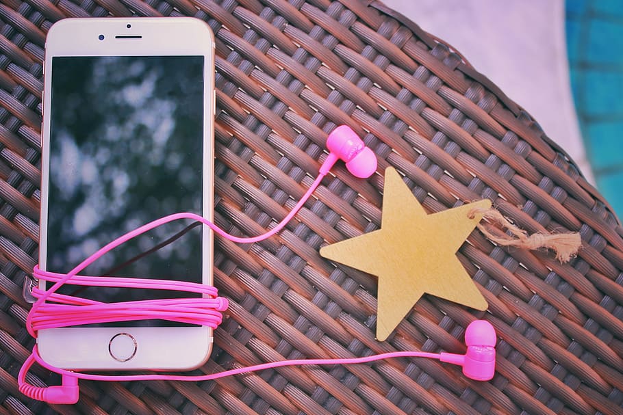 rose gold iPhone 6 with pink earphones on brown wicker table