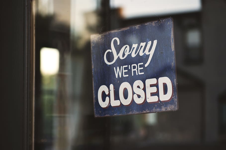 Sorry we're closed signage hanged on glass door, photo of blue wooden Sorry we're Closed signage