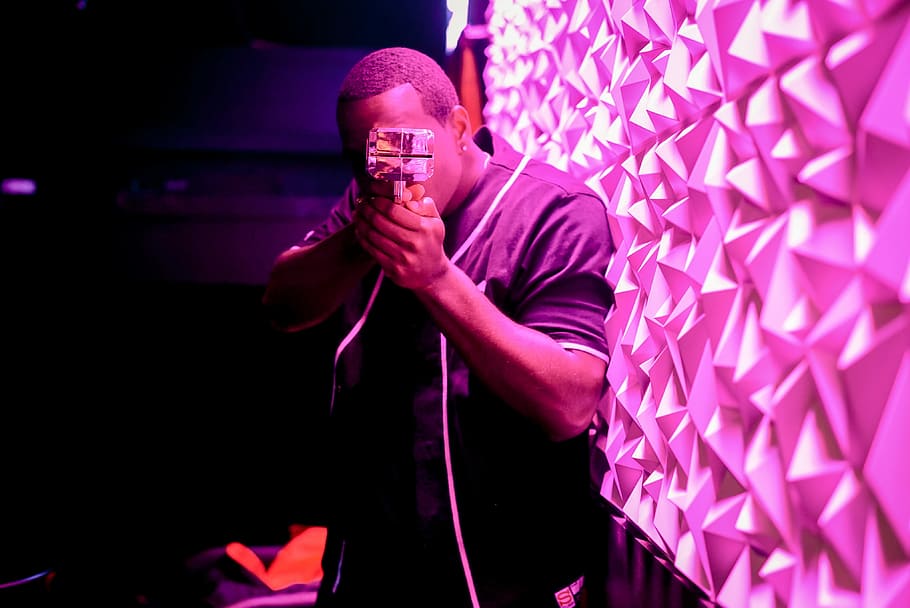shallow focus photography of man holding camera beside pink LED light, man holding action camera near pink wall HD wallpaper