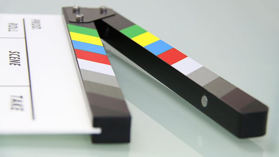 white and black clapperboard on white glass surface, clapper board