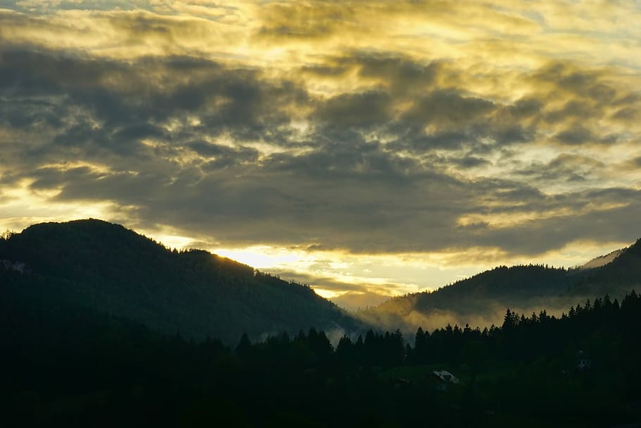 trees and mountains under cloudy sky, sunset, dramatic, clouds HD wallpaper
