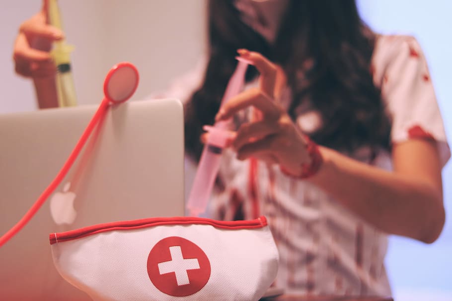 girl holding a syringe near the white and red cross printed decor HD wallpaper