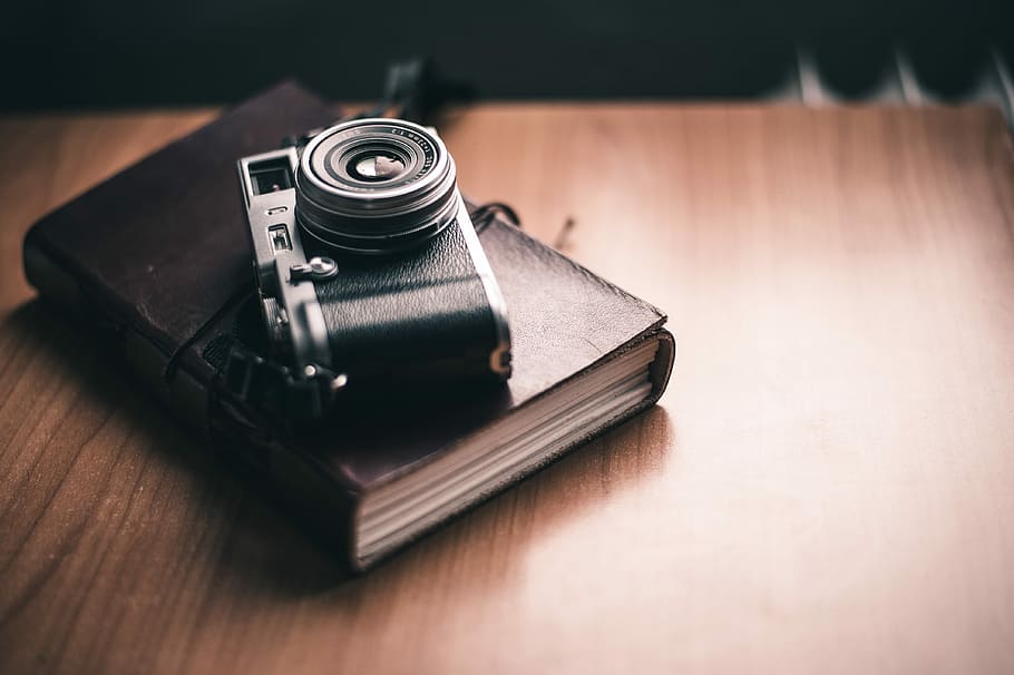 camera on book, closeup photography of film camera on top of hardbound book on table HD wallpaper