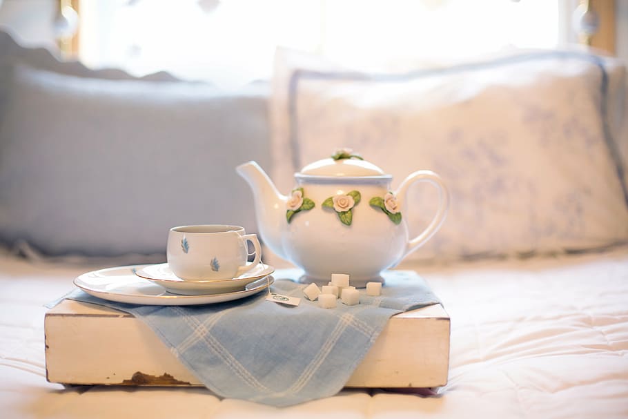 shallow focus photography of white ceramic teapot beside teacup