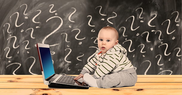 toddler boy wearing hoodie and grey pants sitting beside grey laptop computer HD wallpaper