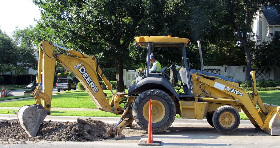 man riding on black and yellow front loader during daytime HD wallpaper
