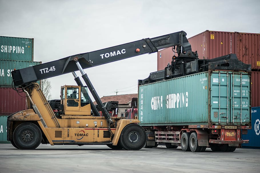 yellow and black Tomac heavy equipment near container tank at daytime HD wallpaper