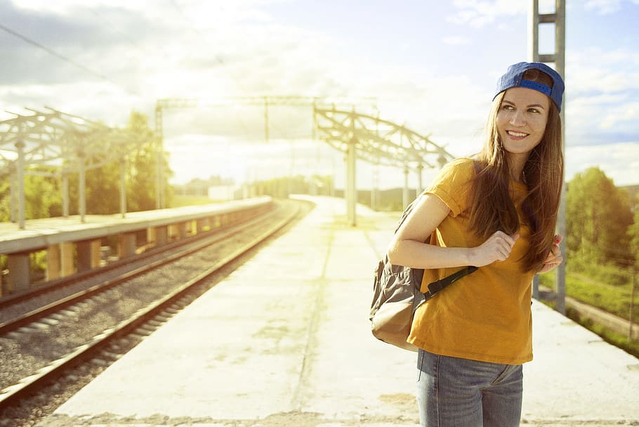 woman wearing yellow crew-neck t-shirt, blue cap, and carrying backpack HD wallpaper
