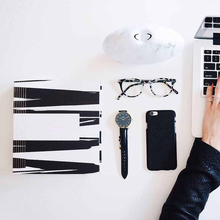 person in black leather jacket using laptop computer beside round gold-colored case analog watch and iPhone in black case HD wallpaper