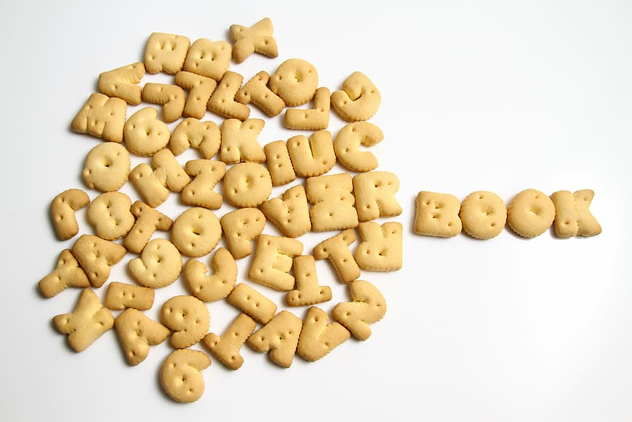 closeup photography of pile of letter biscuits, book, alphabets HD wallpaper