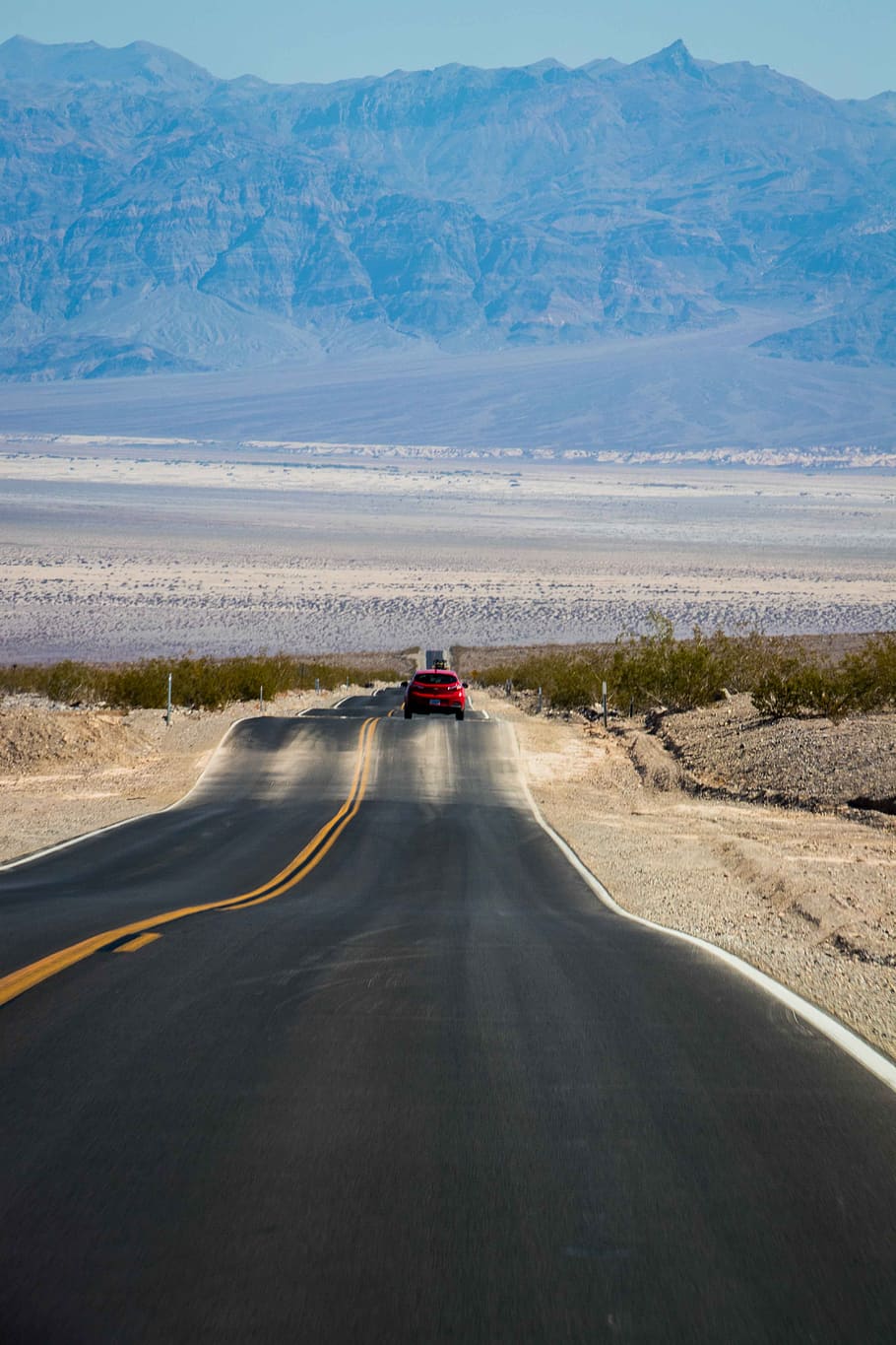 red car on gray concrete road, valley, death, desert, highway