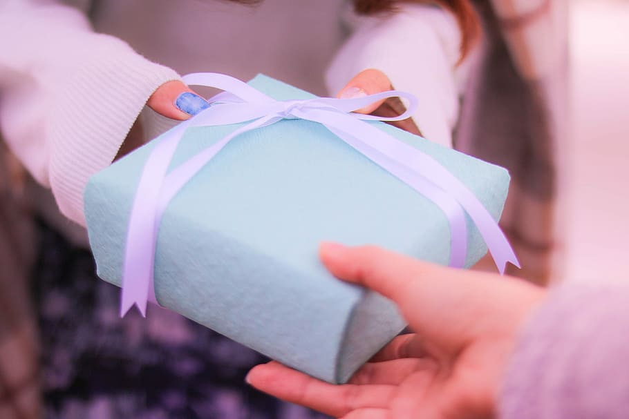 person passing square teal gift box with white bow to another person with blue manicure HD wallpaper