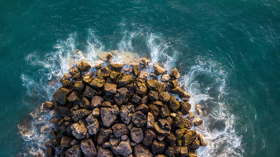 brown rock formation on body of water, pile of rocks surrounded by body of water HD wallpaper