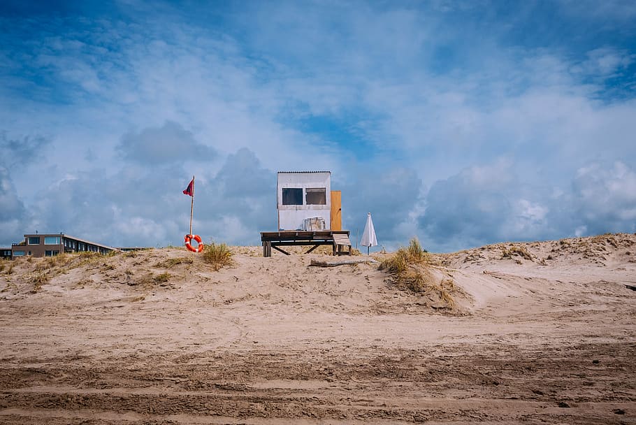 white lifeguard shed beside flag during daytime, white wooden shed near open field at daytime HD wallpaper
