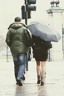 man in green park jacket walking beside woman in black dress with umbrella HD wallpaper