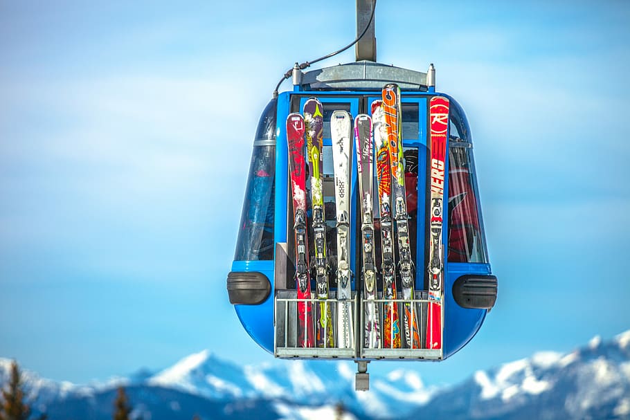 selective focus photography of ski blades on blue cable car, snowskis hanged on cable car HD wallpaper