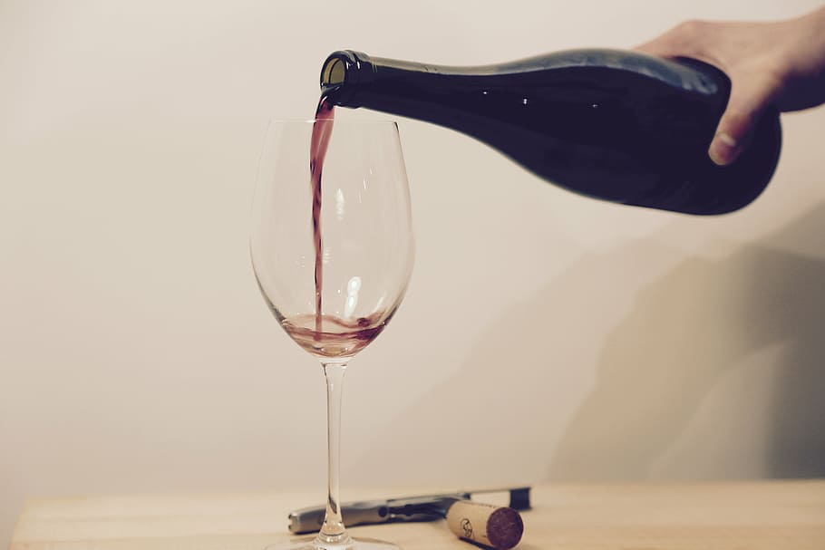 closeup photo of person holding liquor bottle near wine glass HD wallpaper