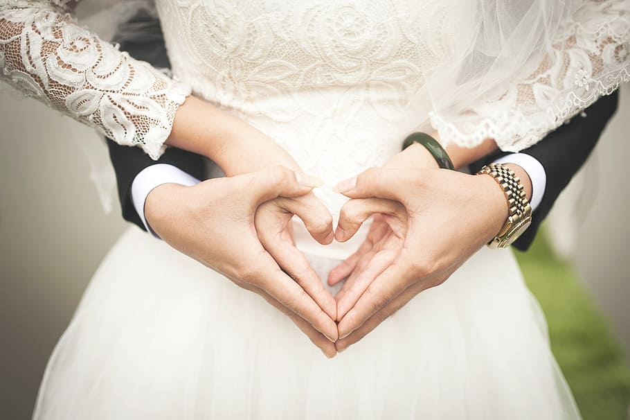 man and woman holding hands doing heart hand sign, love, symbol