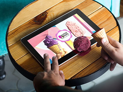 person holding tablet computer showing Nuttie Pops advertisement HD wallpaper