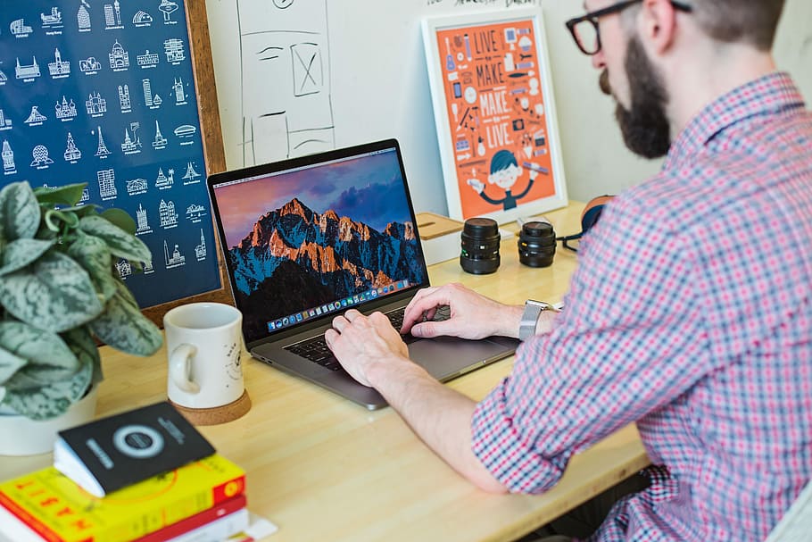 man wearing collared shirt using MacBook, person using MacBook Pro on desk during daytime HD wallpaper