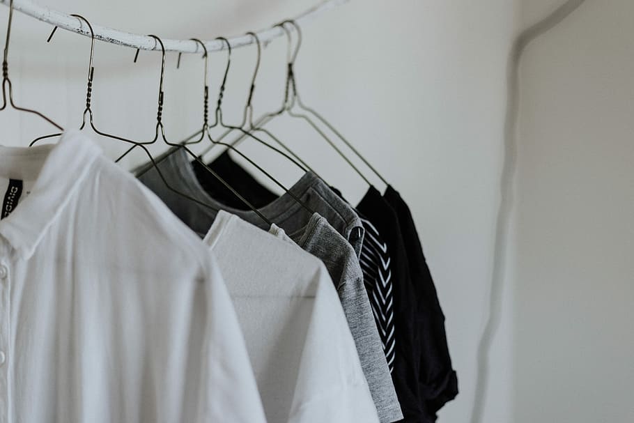 assorted-color shirt hanging beside wall, white polo shirt on clothes hanger