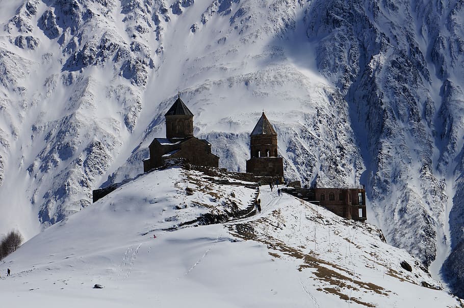The Tsminda Sameba Church in Kazbegi, Georgia, brown concrete building in midst of mountain covered with snow HD wallpaper
