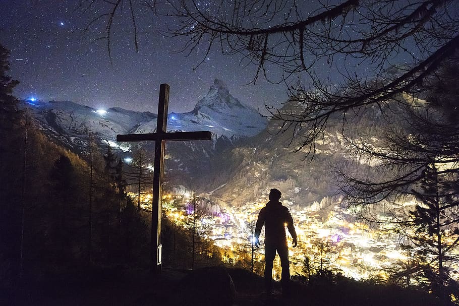 man standing near cross during night, silhouette photo of man standing near cross