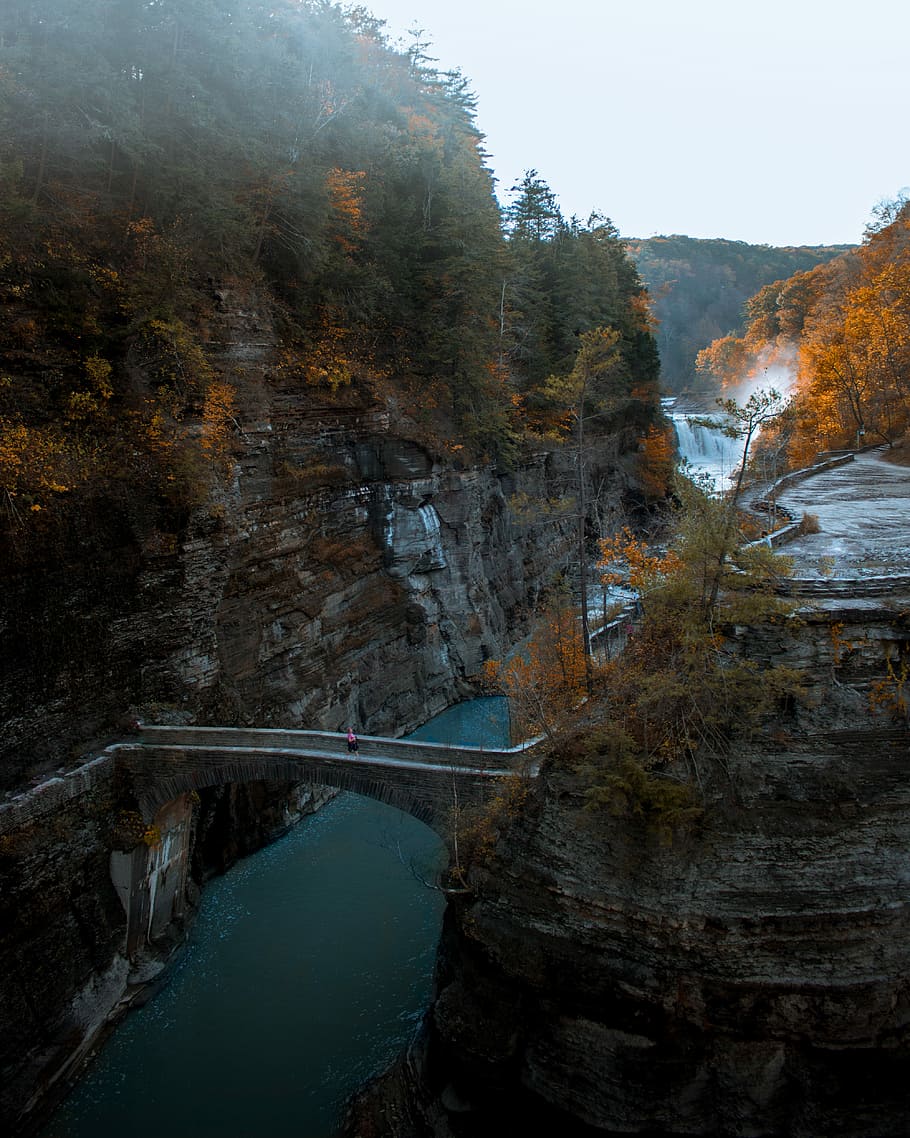 aerial photography of river and bridge, person walking on bridge connecting mountain at daytime HD wallpaper