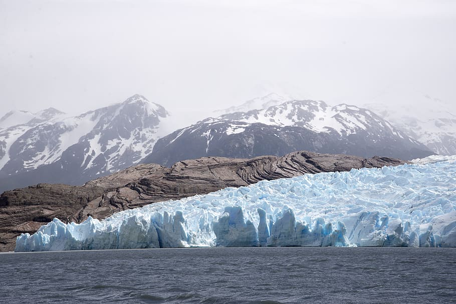 snow mountains during daytime, iceberg on body of water near snow mountains