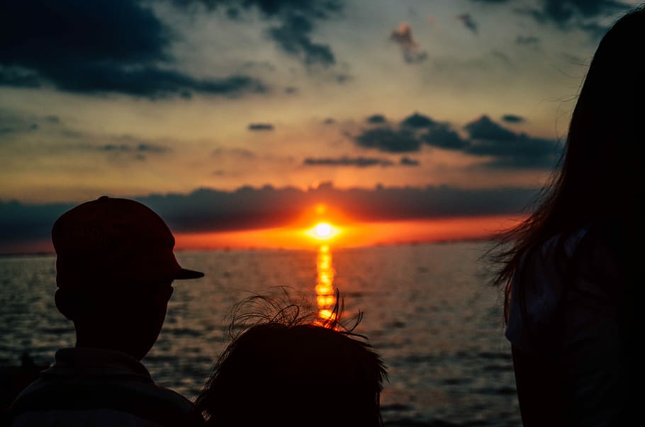 silhouette of children looking on orange sunset above sea, silhouette of three children looking to sunset HD wallpaper