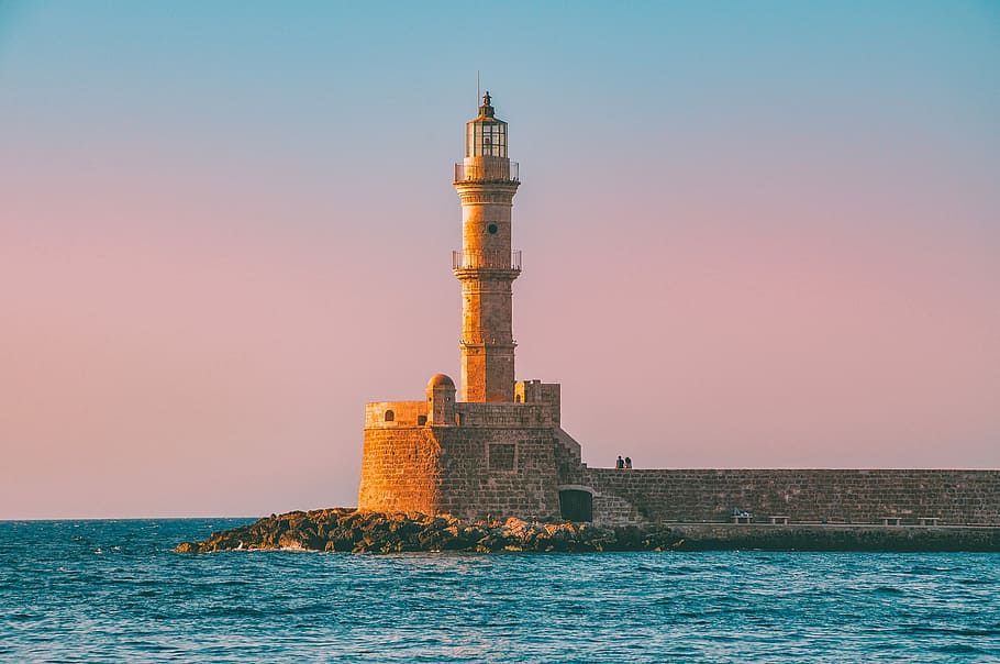 lighthouse with body of water under blue sky during daytime, brown brick tower on sea HD wallpaper