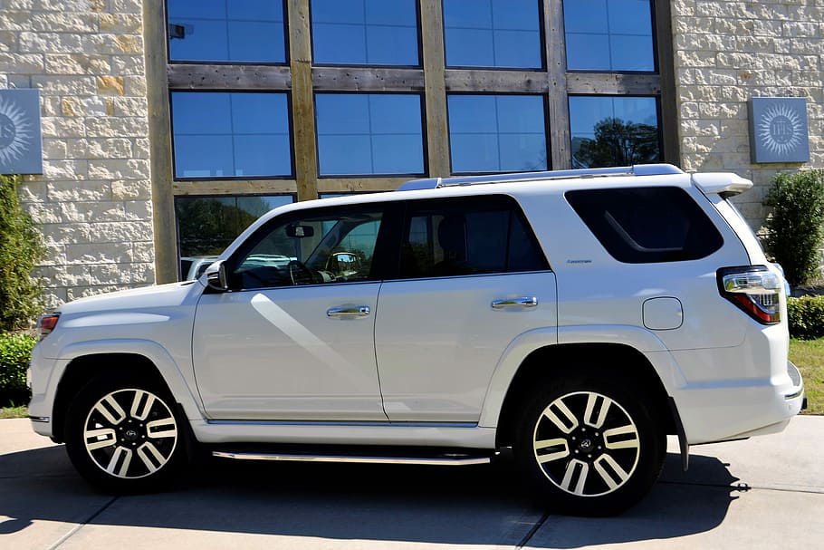white Toyota 4Runner SUV parked beside concrete building at daytime