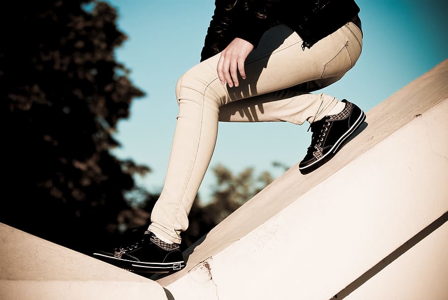 person wearing beige pants sliding on slope, pair of black-and-gray low sneaker