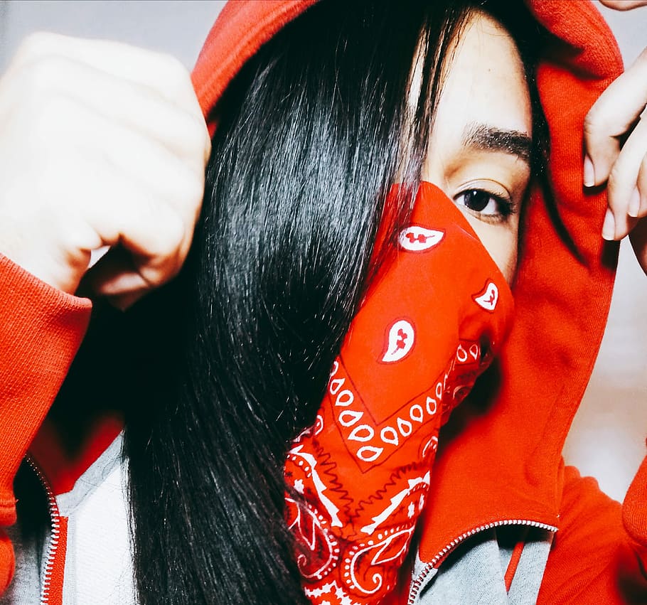 woman wearing red and white paisley scarf taking close-up selfie, person wearing red hoodie and face mask