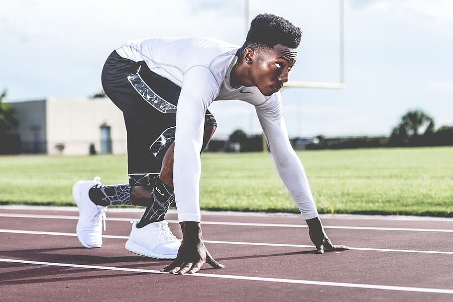 man in black long-sleeved shirt and black shorts getting ready to run at field HD wallpaper