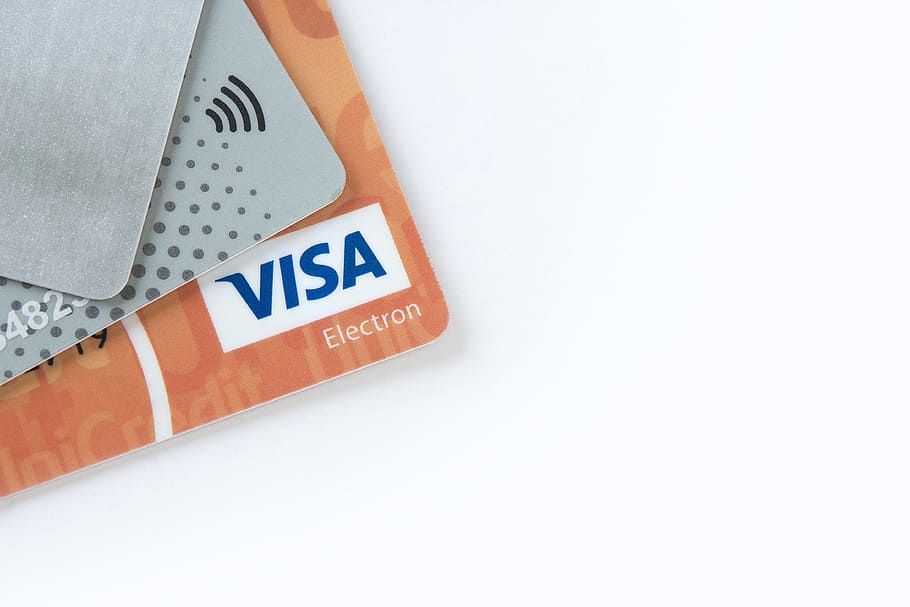 orange Visa card on top of white surface, electronic payments