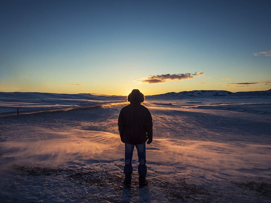 man standing on snow covered ground during sunrise, silhouette photo of man outdoor during golden time HD wallpaper