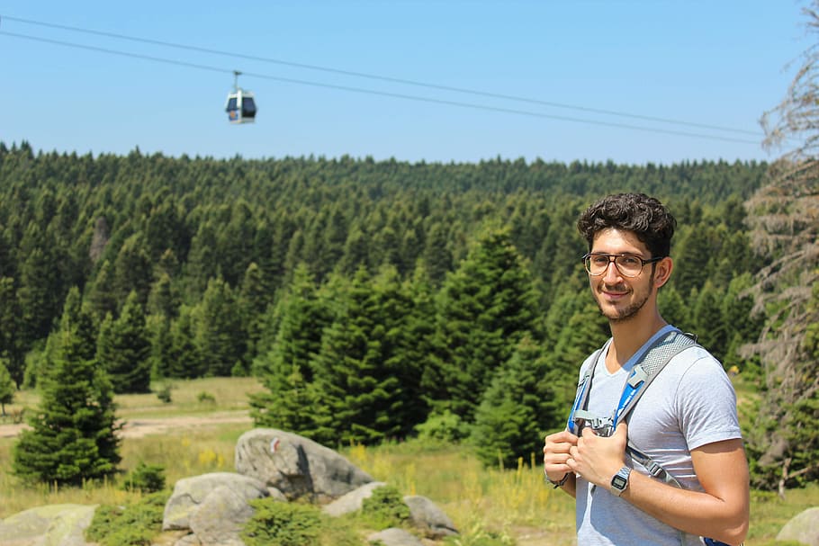 man standing near cable car during daytime, smiling man with blue backpack HD wallpaper
