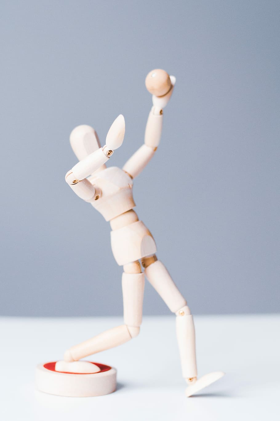 brown manikin figure on white surface, white wooden puppet, ball