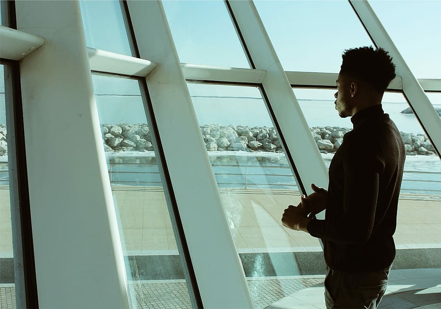 man standing on glass window with white frame during daytime, man standing in front of glass building HD wallpaper