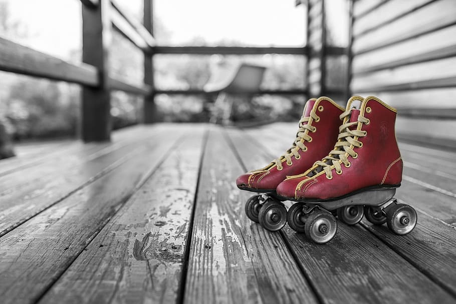 selective color photography of pair of red roller skates, rollerblades