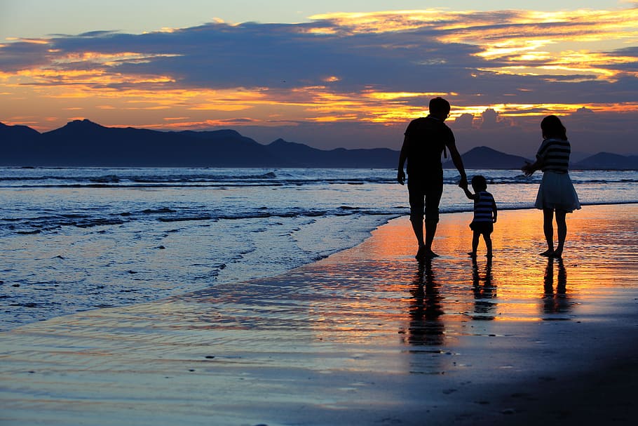 man, woman, and toddler walking on the seashore during golden hour HD wallpaper