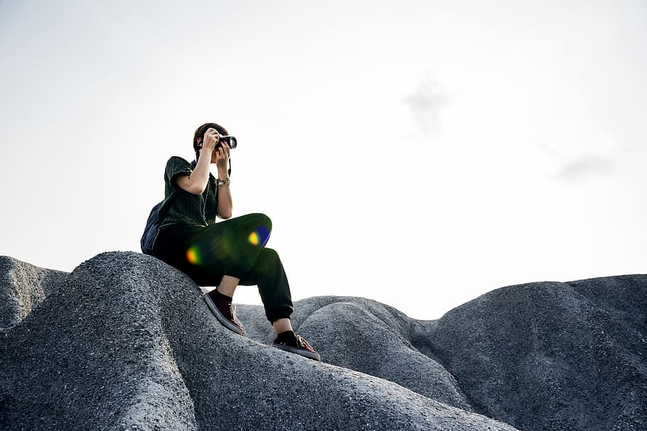 woman holding camera sitting on rock, backpack, calm, casual, HD wallpaper