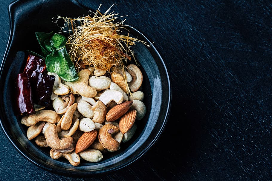 assorted-color nut on vase closeup photo, closeup photo of variety of nuts on black ceramic bowl HD wallpaper