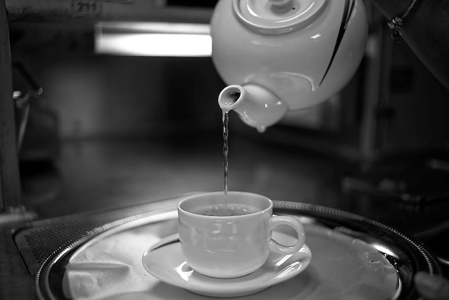 selective focus photography of water poured by pitcher unto white ceramic teacup with saucer on tray HD wallpaper