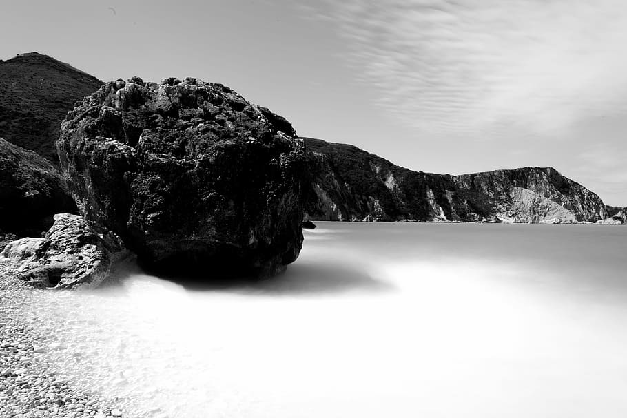 grayscale photo of coastline surrounded with rocky cliffs, grayscale photo of body of water beside mountain HD wallpaper