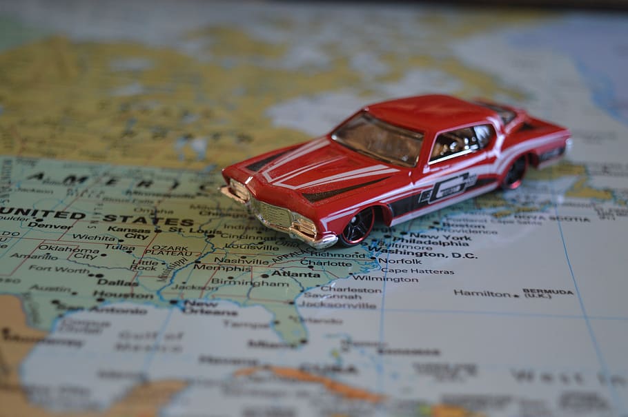 red muscle car die-cast scale model on map sketch, road trip