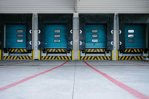 closeup photo of parking lot, four blue warehouse doors, loading bay HD wallpaper