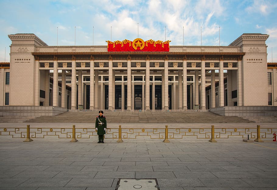 man standing behind brown concrete structure, beijing, china