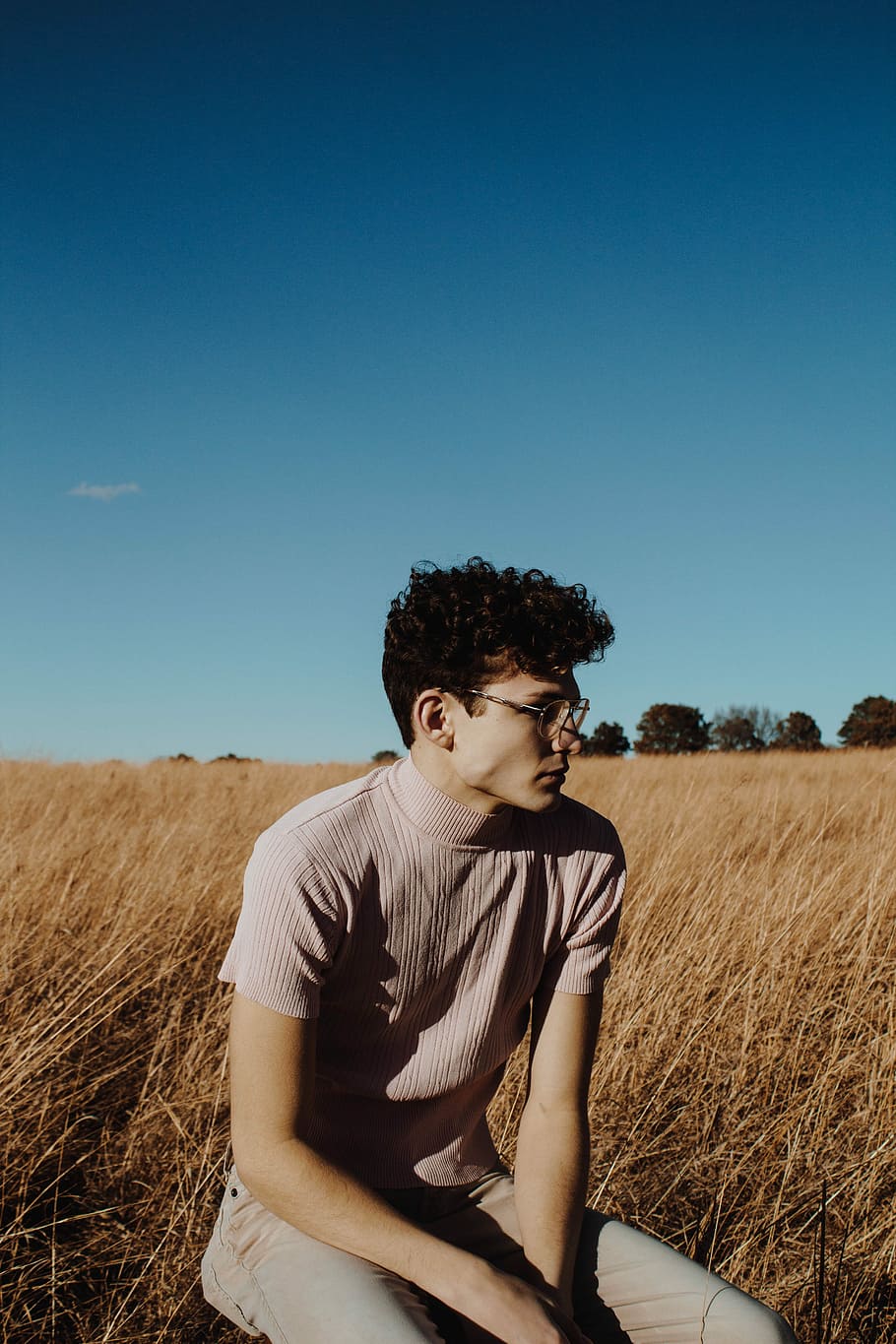 man sitting on ground, man wearing gray turtleneck top sitting in the grass field HD wallpaper